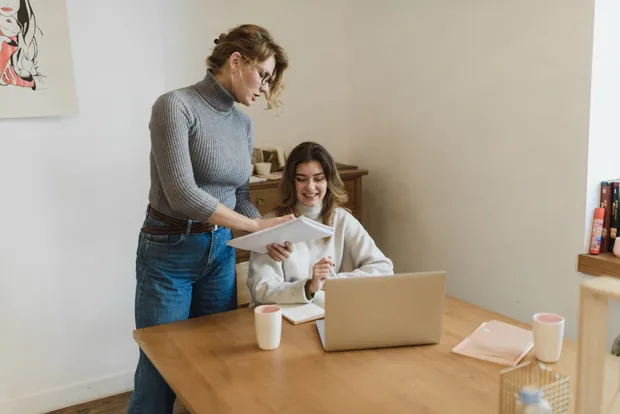 One team member coaching another through a task at a laptop